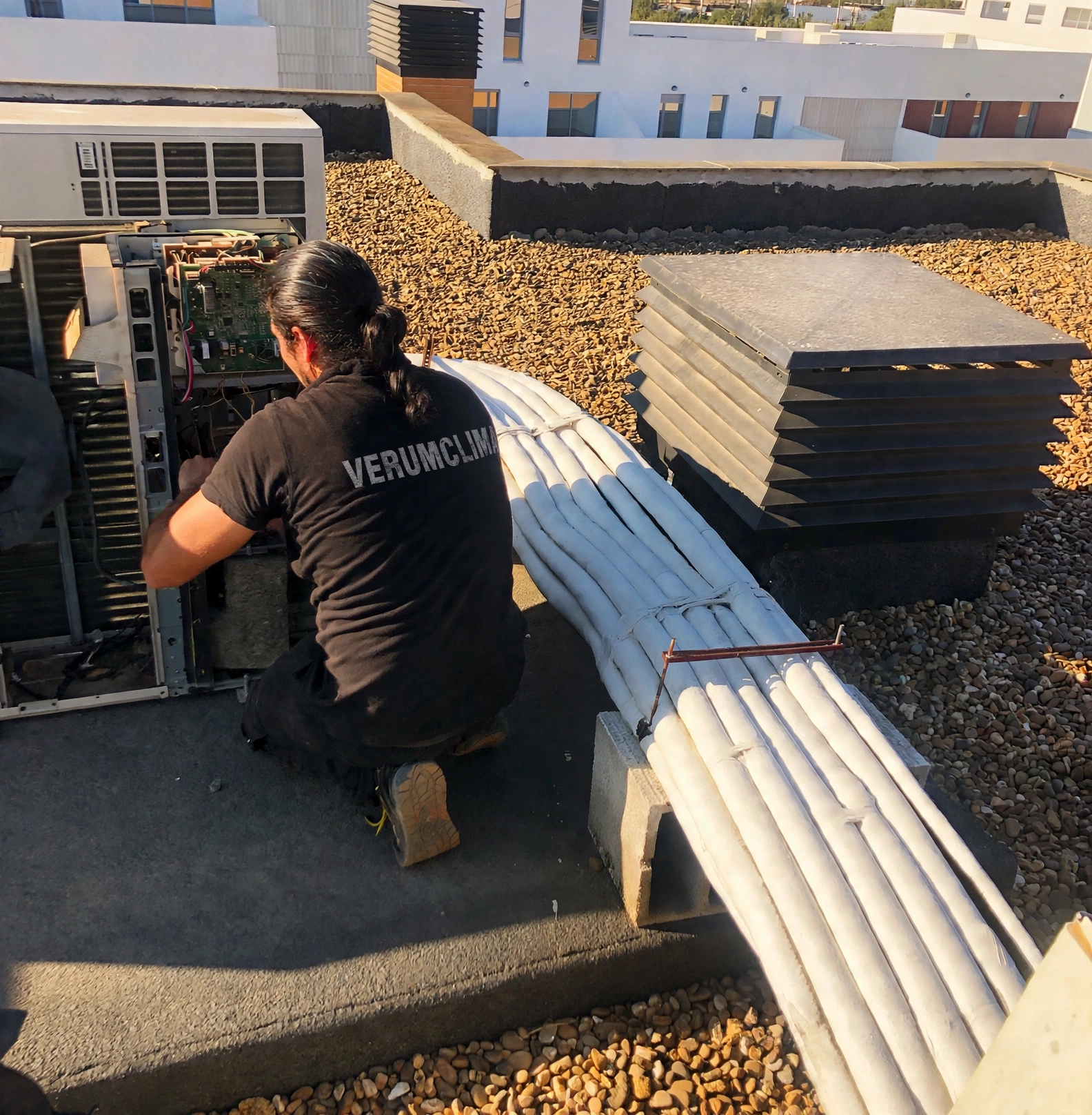 Técnico de Verum Clima conectando una unidad de aire acondicionado en una azotea de Torrefarrera
